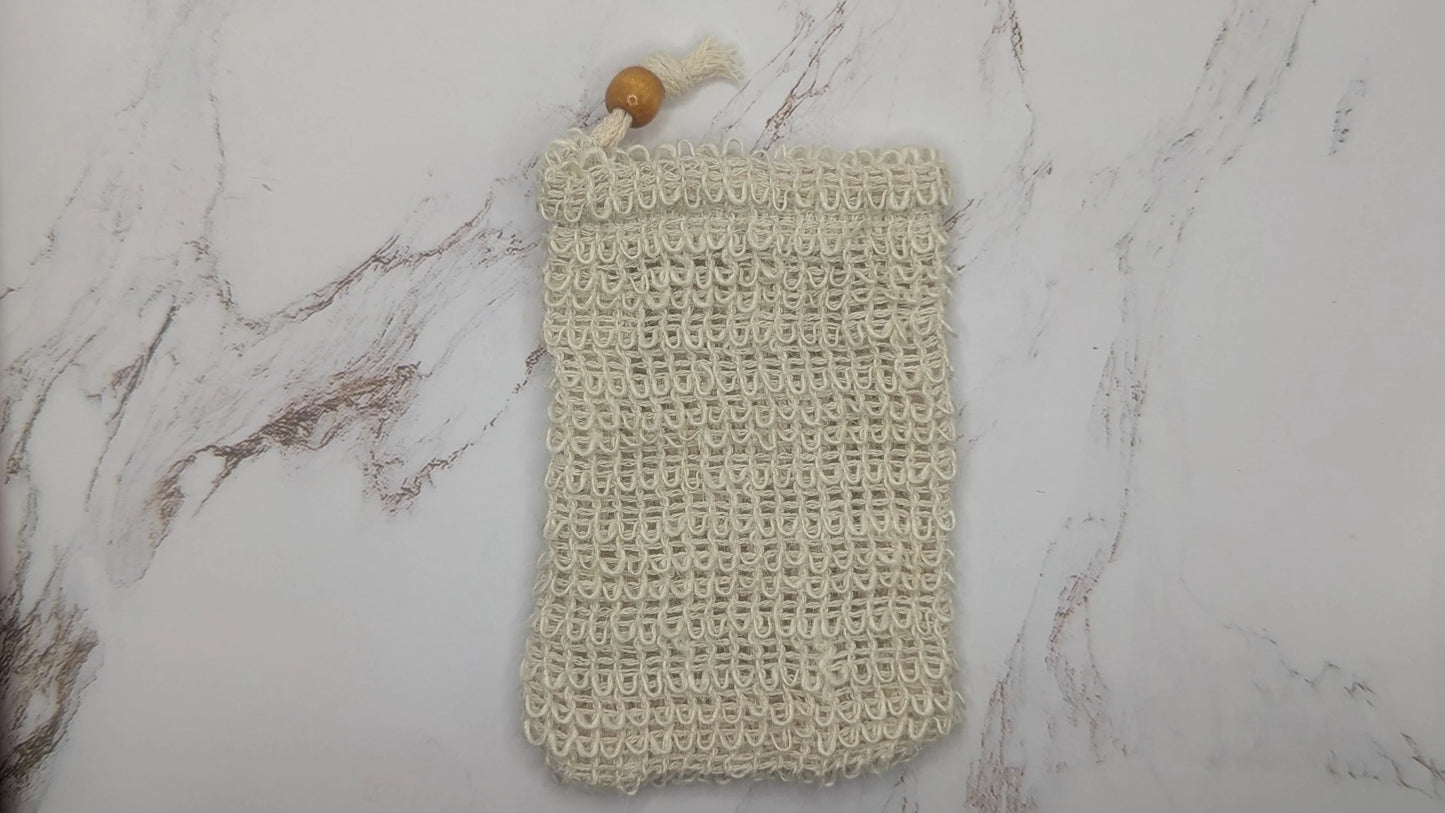 Natural fiber soap saver pouch with wooden bead on marble background
