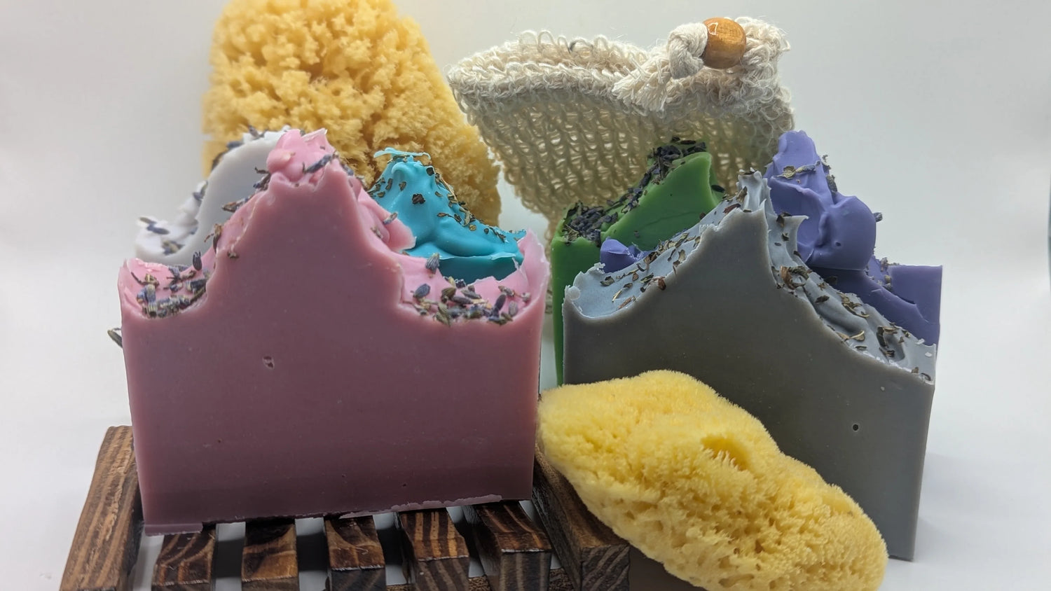 Handmade essential oil soaps with lavender, colorful designs, natural sponge, and soap pouch